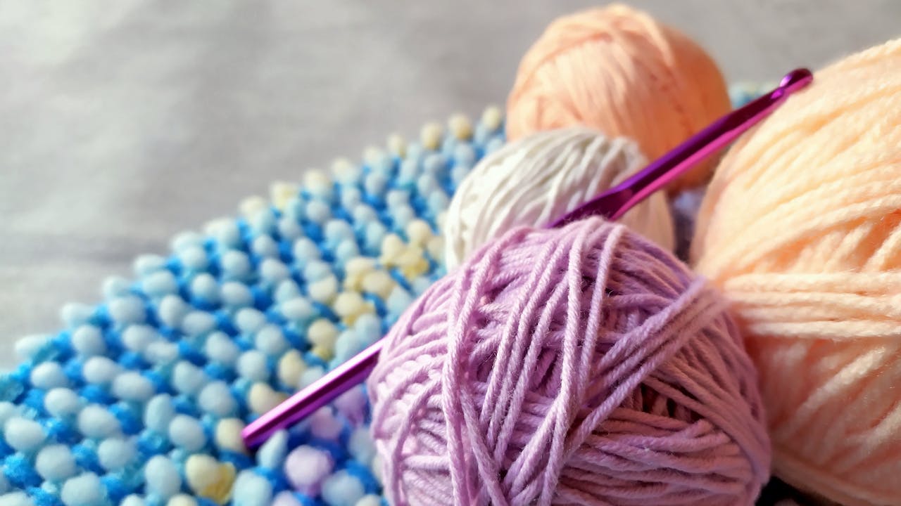 Vibrant yarn and crochet hook on textured fabric. Perfect for craft projects.