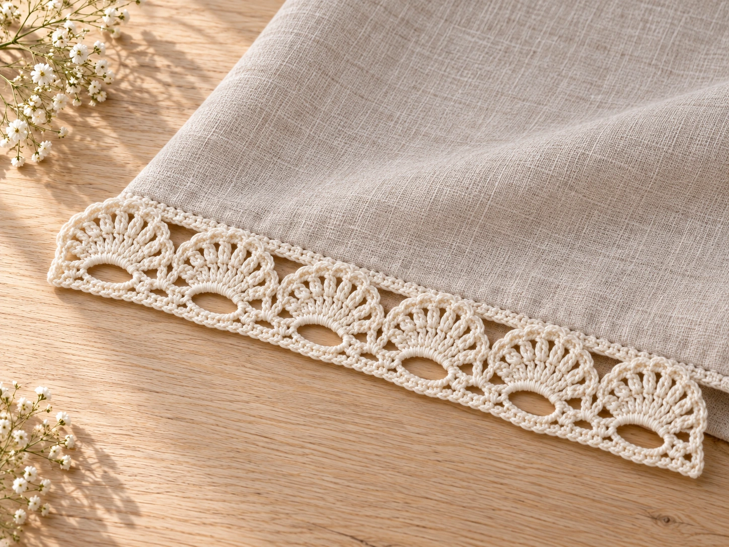 Cream crochet shell lace trim sewn along the edge of a plain natural linen napkin with the rounded fans hanging free
